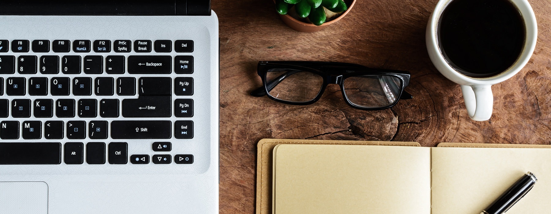 knolling of desktop workspace with coffee mug, laptop, glasses, plant, notebook and pen